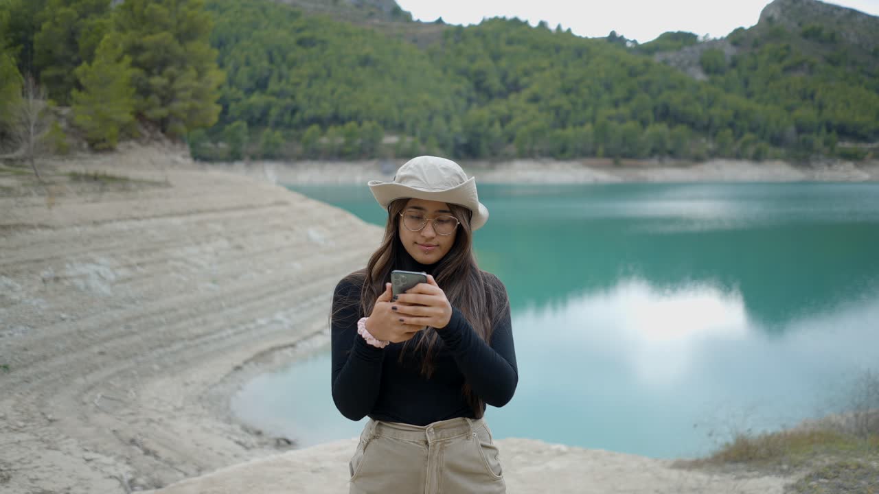 Woman taking a selfie by a lake in the mountains