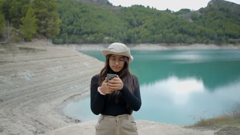 woman taking a selfie by a lake in the mountains