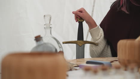 female knight talks sitting at table and holding sword