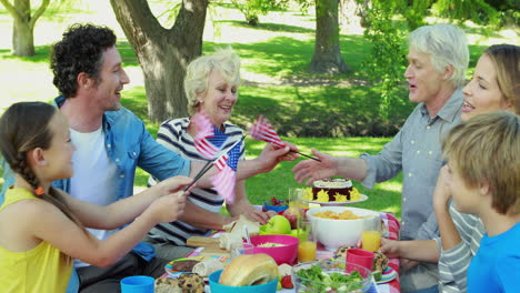 family having picnic and holding american flag