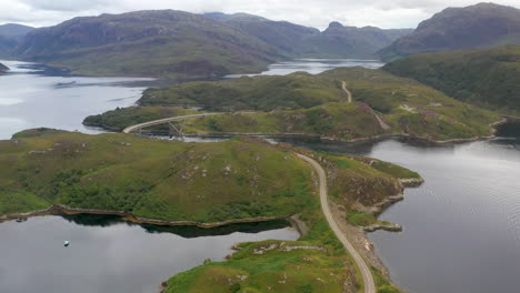 Drone-shot-of-the-Kylesku-Bridge,-following-a-car,-in-north-west-Scotland-that-crosses-the-Loch-a'-Chàirn-Bhàin-in-Sutherland