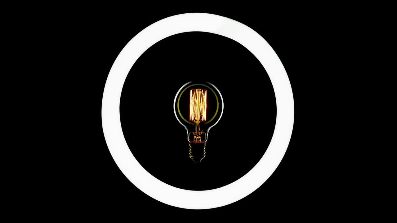 Tungsten light bulb blinking over black background.