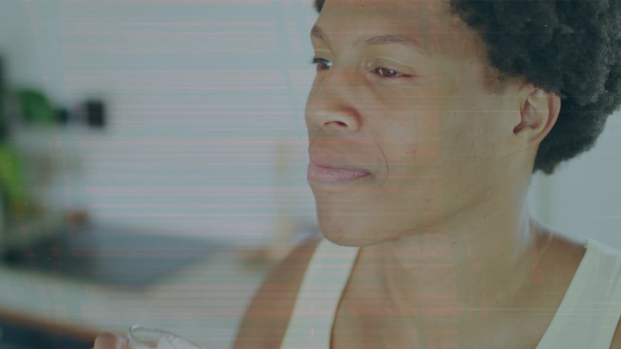 Man raising glass to lips in kitchen, tipping and sipping pale green drink, quenching thirst