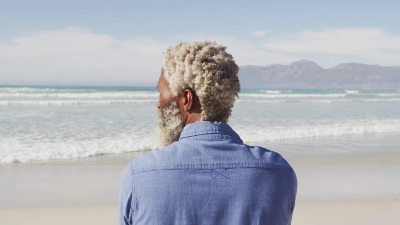 hombre afroamericano de alto nivel mirando lejos en una playa soleada