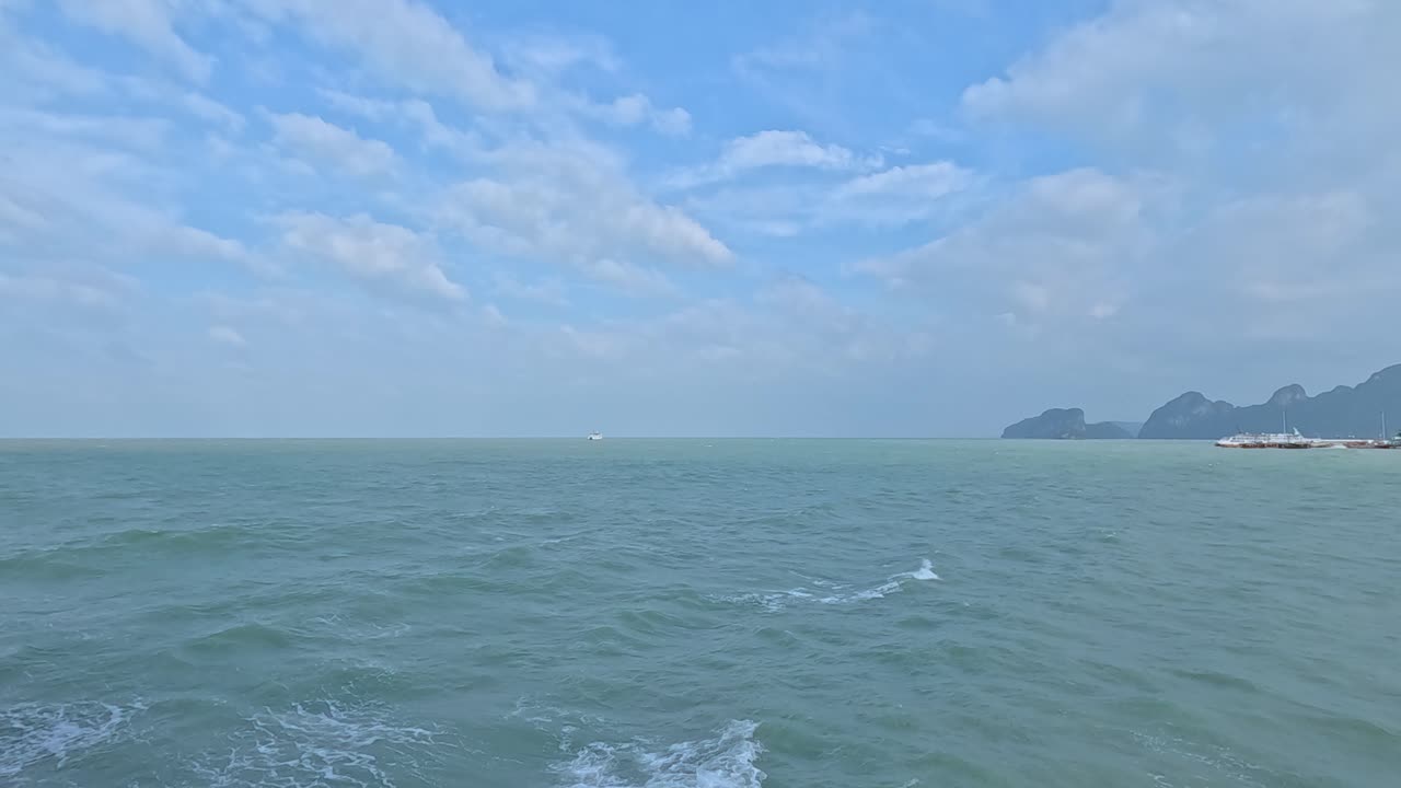 A tranquil ocean scene with gentle waves and distant islands under a bright blue sky, captured in Koh Samui, Thailand