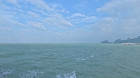 a tranquil ocean scene with gentle waves and distant islands under a bright blue sky, captured in koh samui, thailand