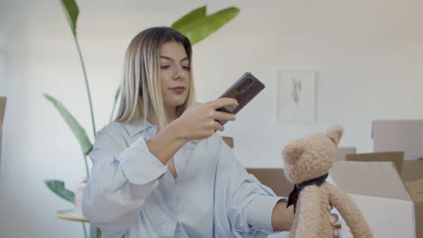 atractiva mujer caucásica tomando una foto comercial de un juguete suave