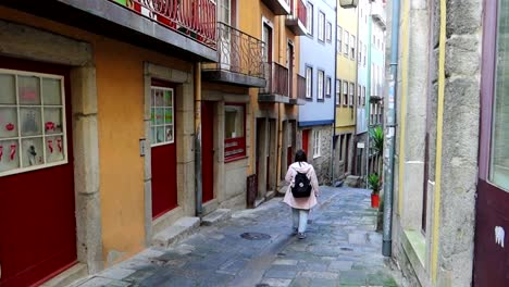 mujer caucásica con mochila caminando por la calle con casas coloridas en oporto