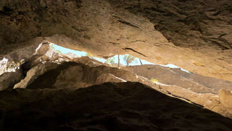 zoom out view from inside a narrow rocky cave, in the caucasus mountains, on a sunny day