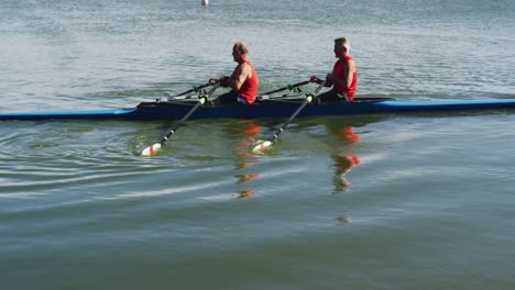 two senior caucasian men rowing boat on a river