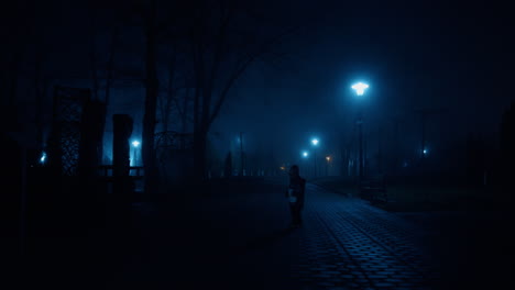 small kid wearing warm clothes walks by the dark alley at night. baby holding a book stops looking at camera.
