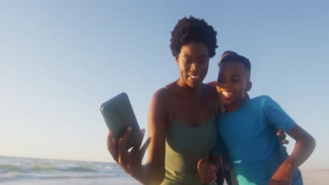 Video-of-happy-african-american-family-taking-photo-on-beach-at-sunset