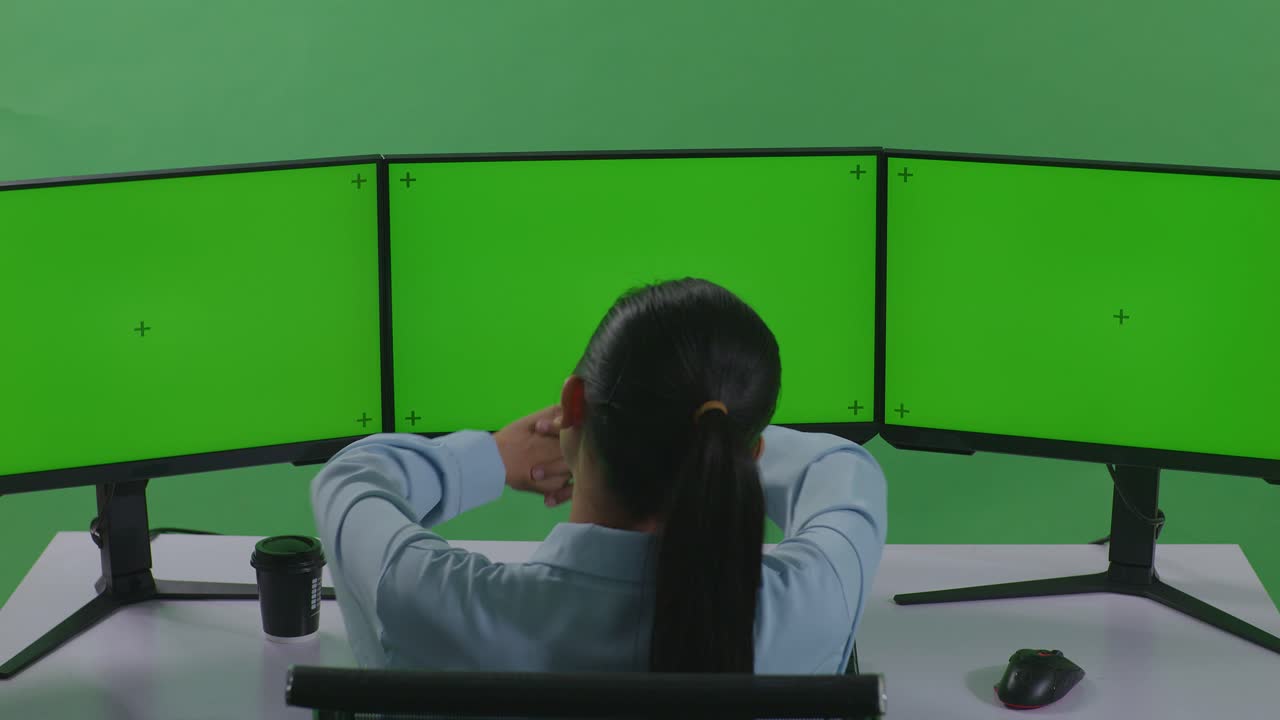 트리플 모니터 컴퓨터 워크스테이션에 앉아 있는 여자