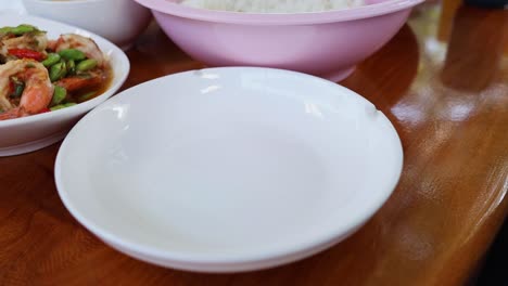 rice being scooped onto a white plate from a bowl