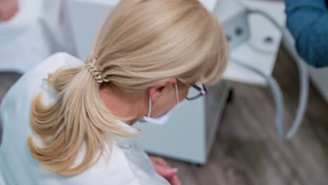 Putting-on-a-protection-mask-on-her-mouth-before-starting-a-massage-of-the-client's-feet-and-a-pedicure