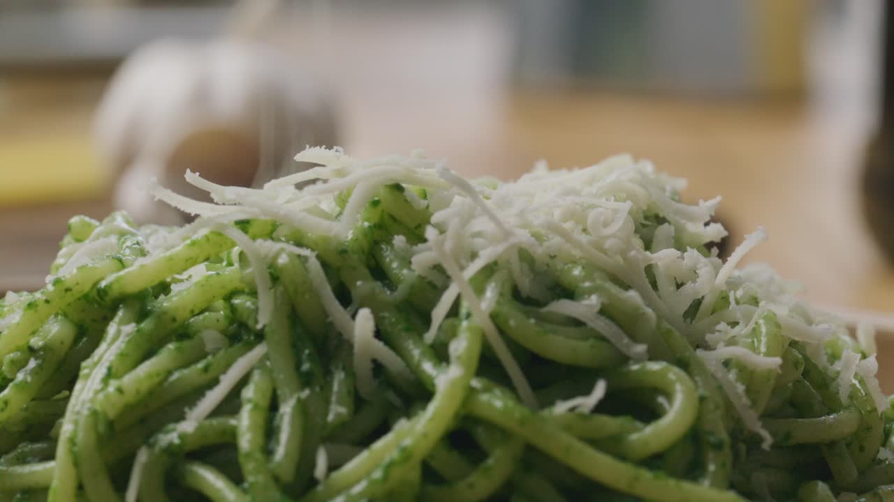 Close-Up of Cheese Being Grated over Hot Pasta with Spinach Sauce