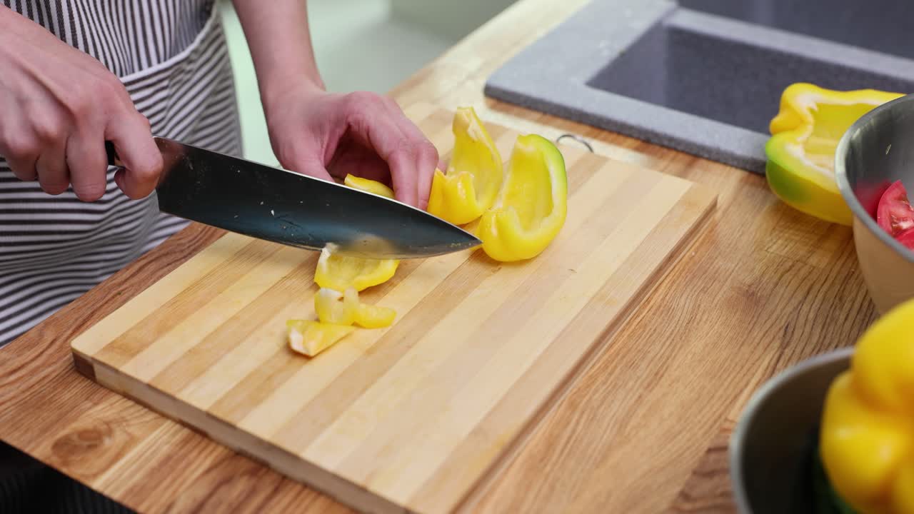 Cutting yellow bell pepper on a wooden board