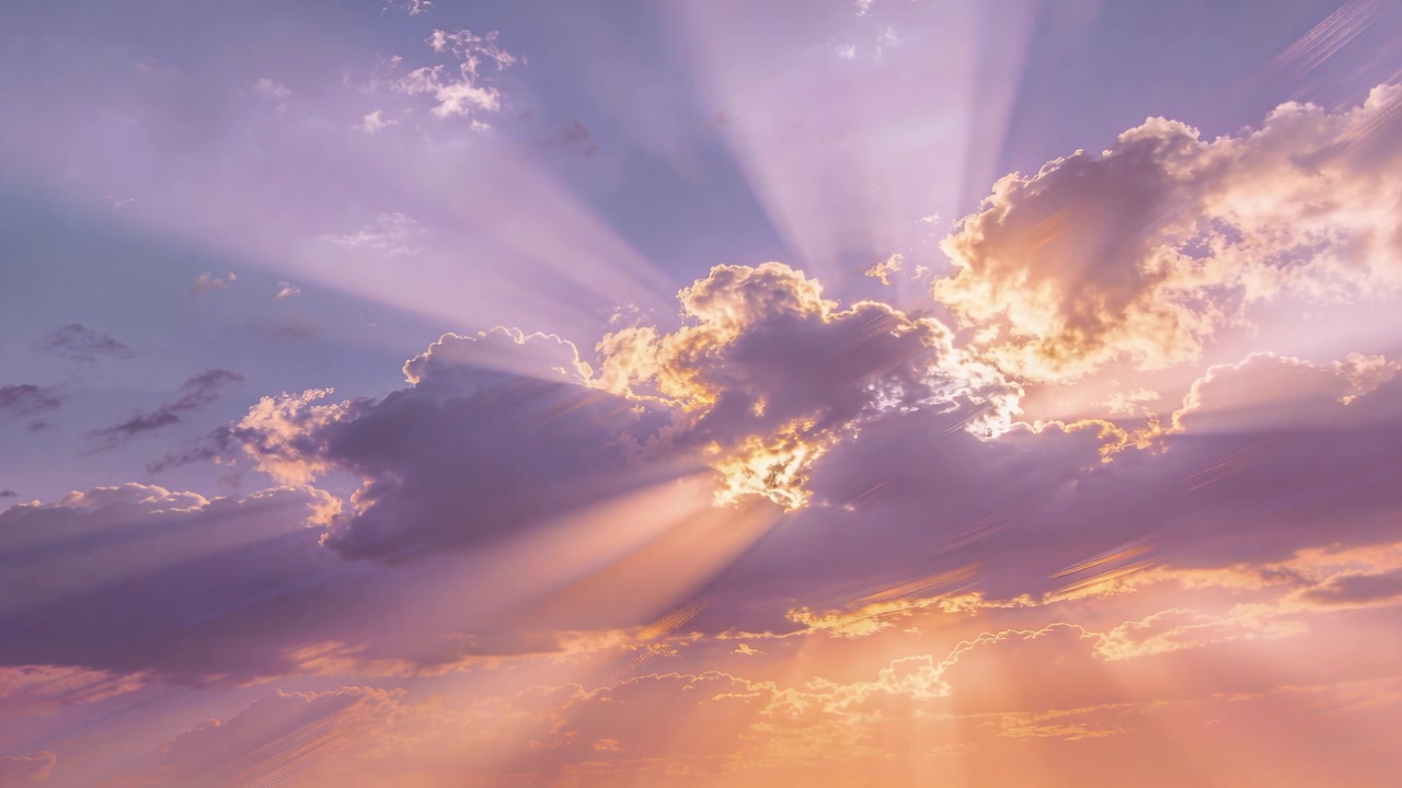 Sole che fa capolino dietro un banco di cumuli centrale, inviando raggi crepuscolari che si irradiano nel cielo all'alba.