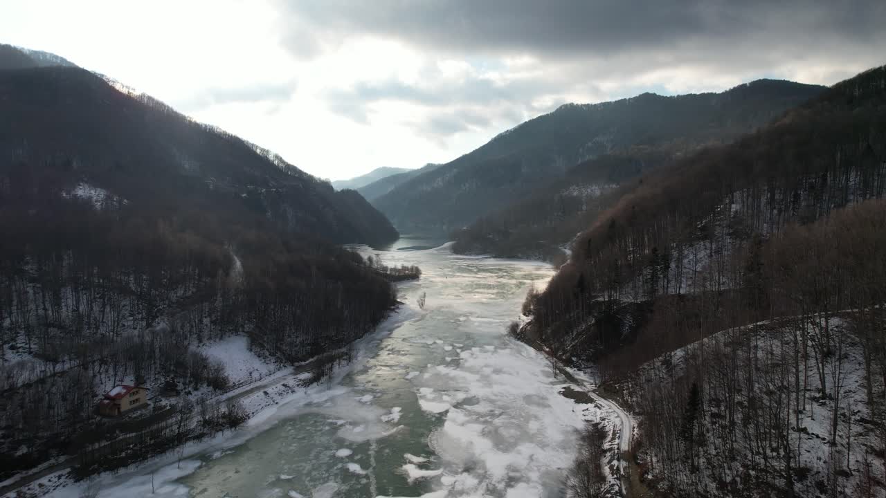 Frozen river in snowy mountains, serene winter scene, calm mood, aerial view