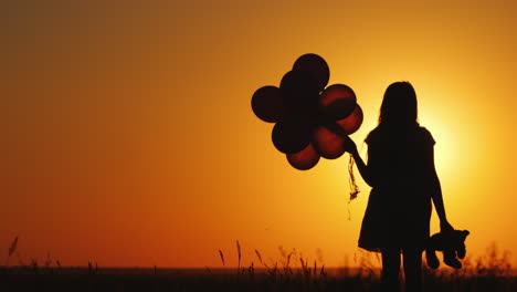 Ein-Kind-Mit-Luftballons-Und-Einem-Teddybären-In-Der-Hand-Steht-Bei-Sonnenuntergang-Abschied-Von-Der-Kindheitserinnerung