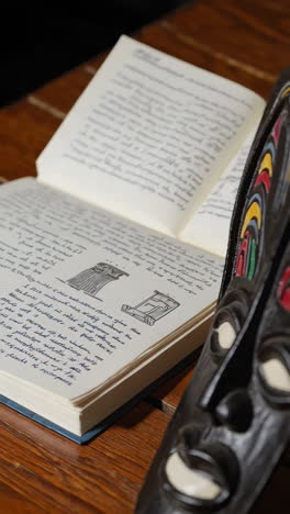 african mask on a wooden table with books