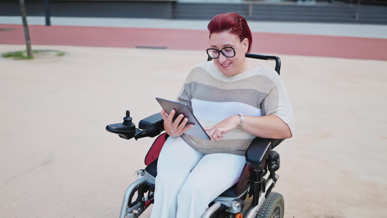 Happy Woman in Motorized Wheelchair Using Digital Tablet Outdoors