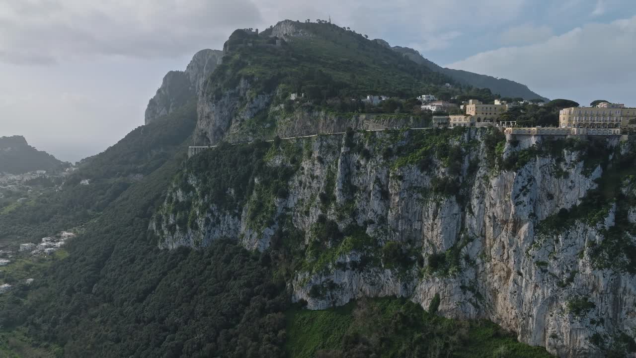 은 하늘 아래 울창한 초록색과 역사적인 건축물이 있는 카프리의 절벽 풍경