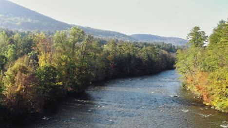 Aerial-shot-of-Housatonic-river-passing-by-the-hilly-terrain-in-Litchfield-County,-Connecticut,United-States-on-a-sunny-morning