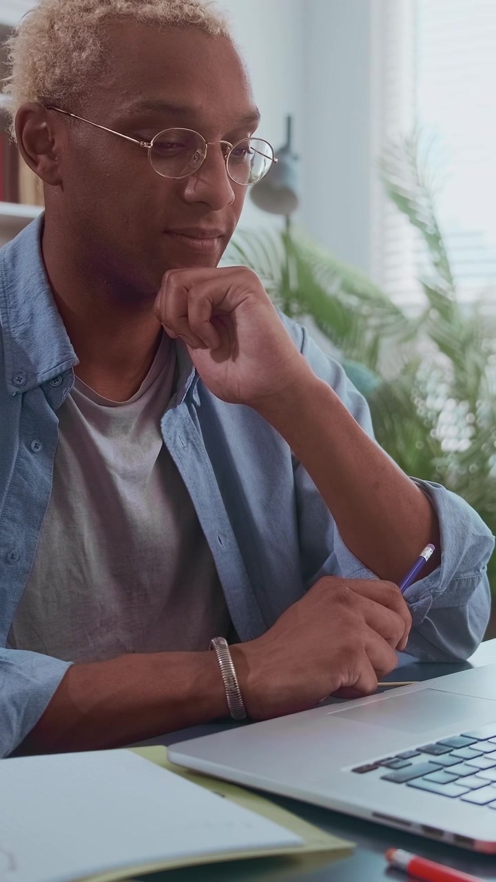 Focused african american man with blonde curly hair and glasses working on