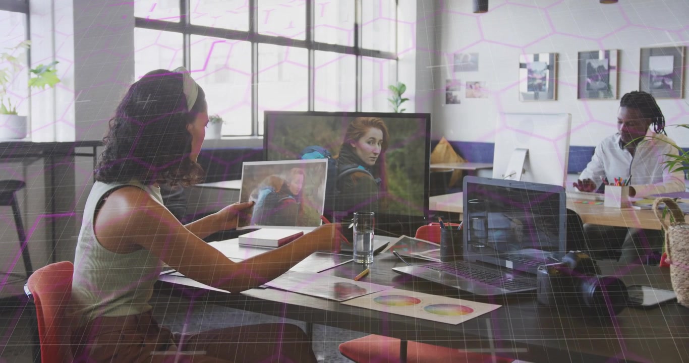 Designer holding printout and aligning it with monitor, swapping prints for design comparison