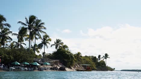 Tilt-up-shot-of-a-guide-tourist-transport-boat-docked-on-the-tropical-Restinga-beach-near-the-tropical-coastal-town-of-Barra-do-Cunhaú-in-Rio-Grande-do-Norte,-Brazil-on-a-warm-sunny-summer-day