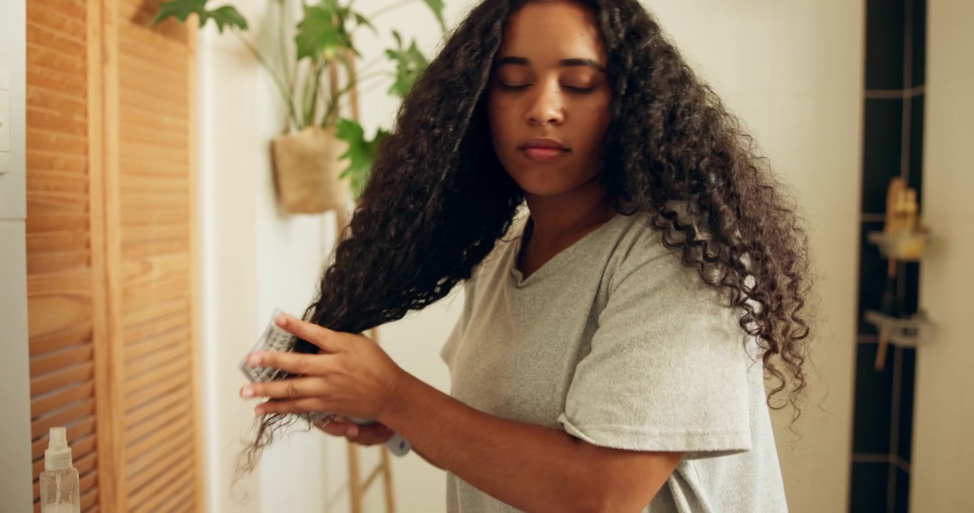 Young Woman Applying Hair Product and Combing Curly Hair