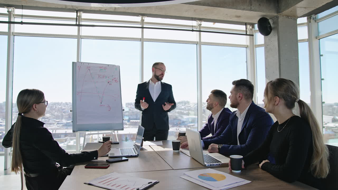 Male speaker communicating with his coworkers at office. Business meeting for planning and building strategies at work. City view at backdrop.