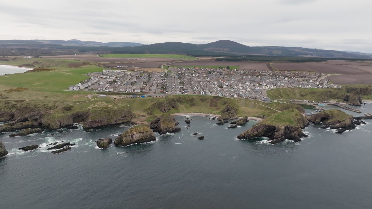 Aerial revealing shot of Portknockie village, a traditional Scottish fishing village overlooking the North Sea, Scotland