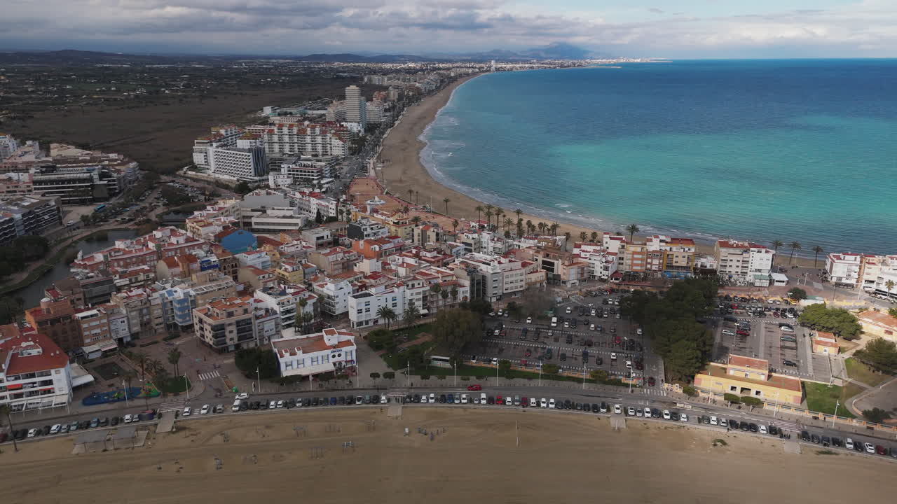 Luftfoto af Playa Sur kystlinje med bølger, der ruller ind på sandstrand under solrig blå himmel.