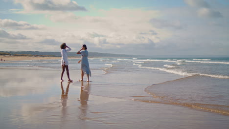 vertical view lesbian couple walking beach in summer. best friends resting ocean