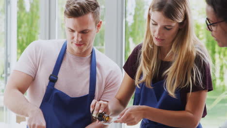 male and female adult students measuring ingredients in cookery class in kitchen