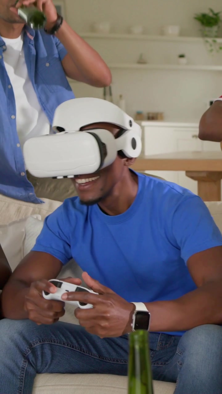Vertical video: Putting on white VR headset man in blue tee playing gamepad at home for game night