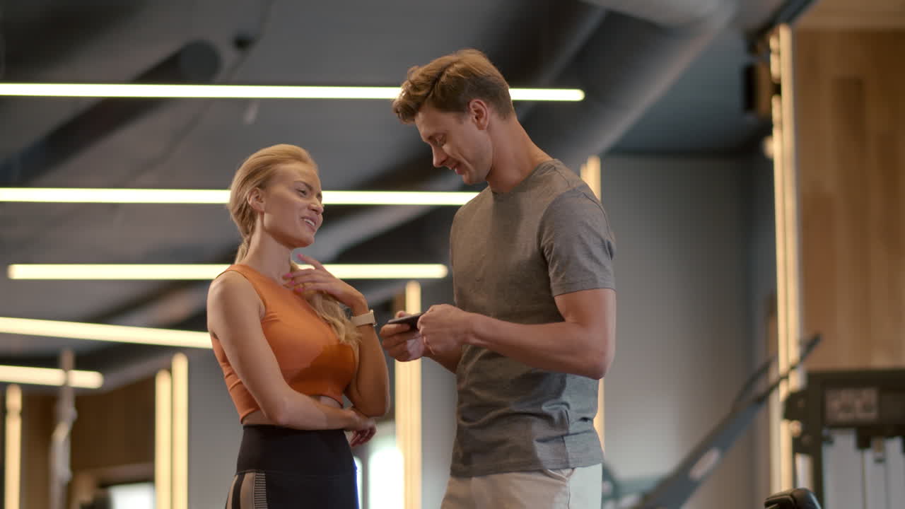 Beautiful fit couple flirting at gym. Fit man writing phone number in sport club