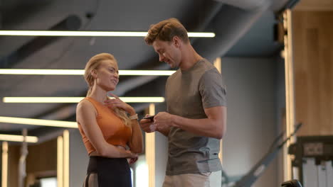 beautiful fit couple flirting at gym. fit man writing phone number in sport club