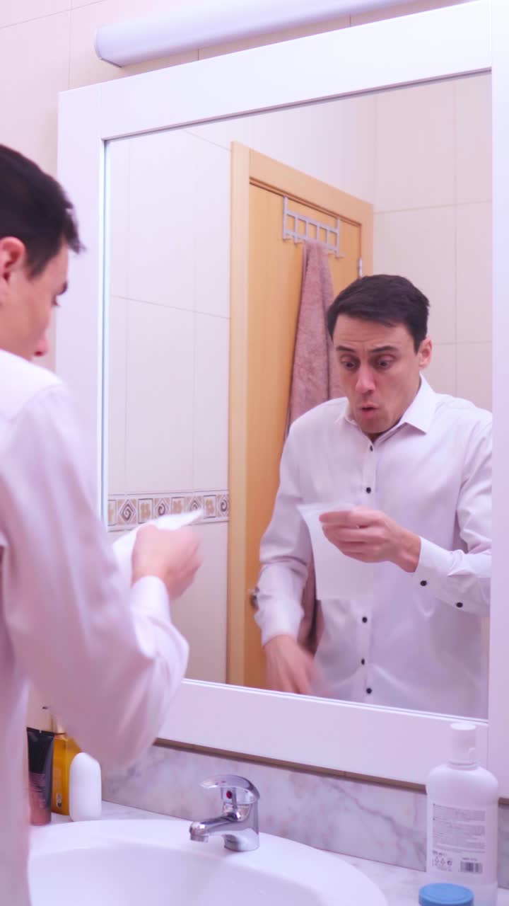 Businessman blowing nose and getting scared in bathroom mirror