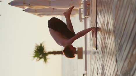 Young-guy-I-in-black-shorts-stands-on-his-hands-on-a-special-rug-during-his-meditation-on-a-private-beach