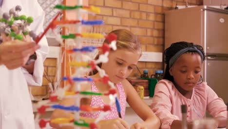 teacher assisting student in studying molecule model in laboratory