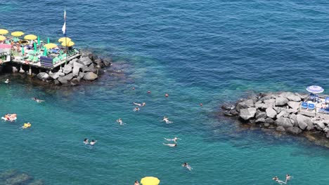 people swimming near a rocky beach in sorrento