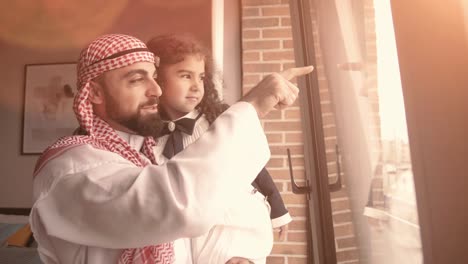 little arabic girl and her father i looking through the window. isolation at home for self quarantine. concept home quarantine, prevention covid-19. coronavirus outbreak situation