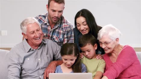 familia de varias generaciones usando una computadora portátil en el sofá