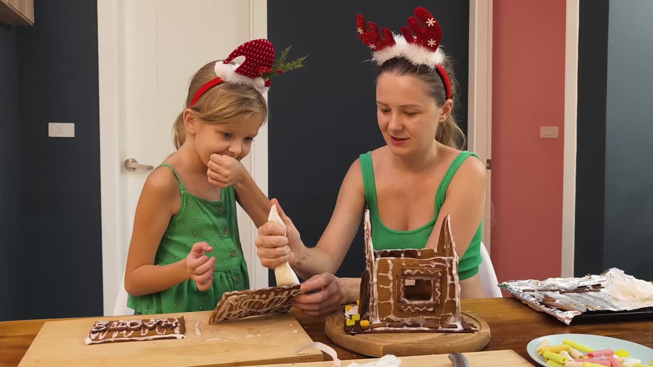 madre e hija decorando una casa de pan de jengibre