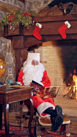 santa claus reading a book at christmas. decorated room and santa sitting in a chair with a magic book on fireplace background. christmas spirit. holidays and celebration concept. vertical video