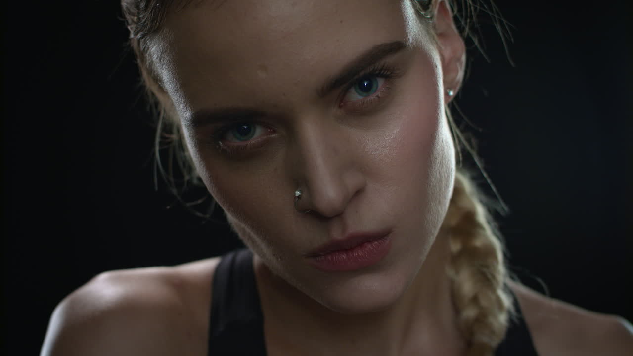 Aggressive woman biting lips looking to camera on black background