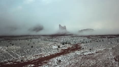 aerial shot tilting up from the snow covered desert floor to reveal low lying clouds covering utah's mountainous horizon